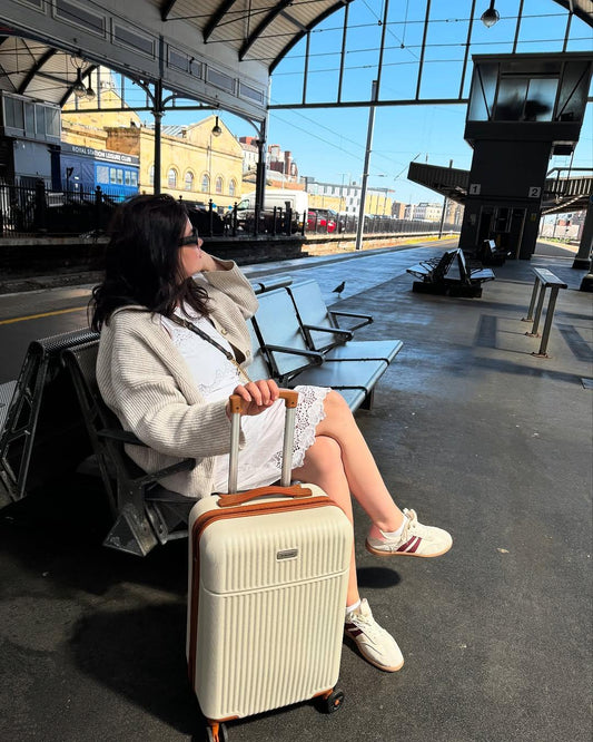 Woman at train station with Tavoxda lightweight suitcase, durable shell, silent wheels