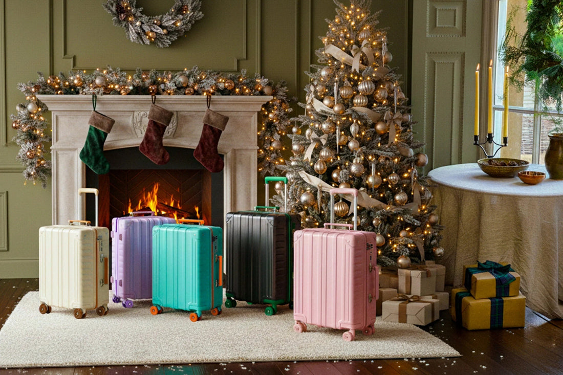 Tavoxda lightweight luggage in assorted colors by a Christmas tree and festive fireplace setting